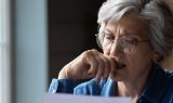 Senior kvinde med briller ser eftertænksomt på papir
