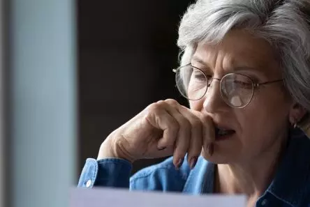 Senior kvinde med briller ser eftertænksomt på papir
