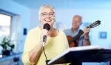 Glas senior kvinde med briller synger i mikrofon
