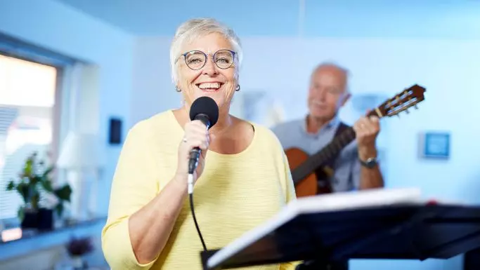 Glas senior kvinde med briller synger i mikrofon