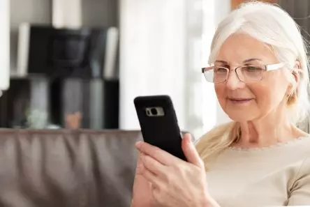 Seior kvinde med briller ser på sin smartphone
