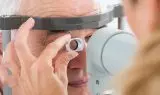 Senior mand får synsundersøgelse med apparat foran øjnene