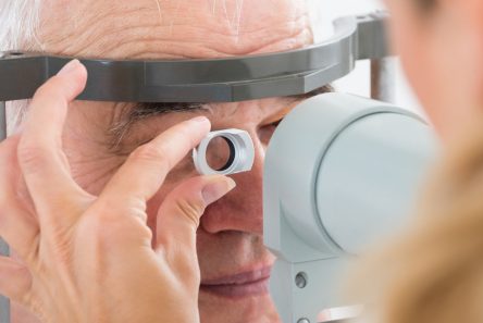 Senior mand får synsundersøgelse med apparat foran øjnene