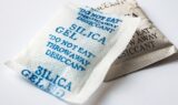 To små poser med silica gel, påtrykt DO NOT EAT, THROW AWAY, DESICCANT, ligger på en hvid overflade - husk genbrug: brug dem som en smart opbevaringstips til at holde dine ting tørre!.