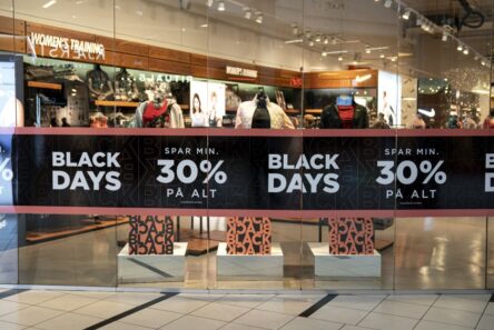 Butiksvinduet viser store sorte bannere med BLACK DAYS og 30% PÅ ALT i hvid tekst, der reklamerer for 30% rabat. Mannequiner og tøj er synlige inde i den stærkt oplyste butik via automatisk kladde.