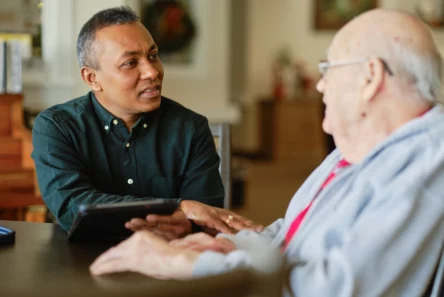 En mand diskuterer udfordringer i plejepersonale med en anden mand.