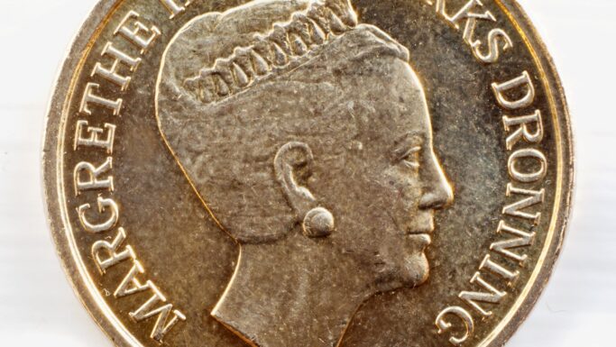 Et nærbillede af en 20-kroners mønt med profilen af en kvinde med øreringe og en krone og påskriften MARGRETHE DANMARKS DRONNING - detaljer, der hjælper med at grave i, hvordan man kan genkende falske mønter.