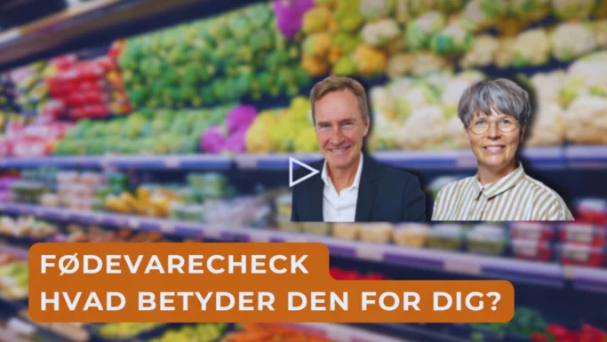 To smilende voksne, en mand i jakkesæt og en kvinde med briller, står foran slørede produkthylder. Et orange banner spørger: Fødevaretjek Hvad betyder den for dig? Få svar på dine spørgsmål om fødevaretjek her.