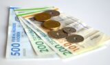 Flere danske kronesedler (500 og 200) og mønter er arrangeret på en hvid flade og symboliserer opsparing eller de midler, man kan få, når man går på folkepension.