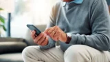 En ældre herre sidder med en smartphone