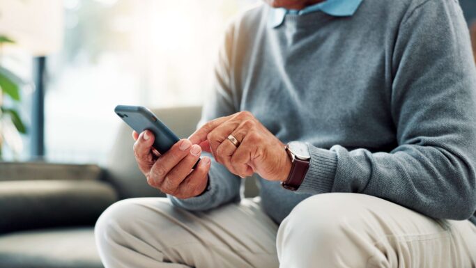En ældre herre sidder med en smartphone
