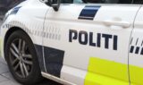 Et nærbillede af en hvid Politiet-politibil med ordet POLITI på siden, gule refleksmærker og et snavset forhjul – en bil, man ofte ser, når betjente rykker hurtigt ud til anmeldelser om svindlere, der har ældre borgere som mål.