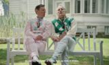 To ældre mænd i farverige trøjer sidder på en hvid bænk uden for et hus. Den ene holder et vinglas, og der vises danske undertekster nederst på skærmen. Scenen udspiller sig i en solrig have med græs og planter, hvilket antyder en afslappet samtale om alkohol og sundhed – måske endda en diskussion af Kræftens Bekæmpelses råd.