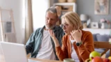 En mand og en kvinde kigger overrasket på en bærbar computer, mens de gennemgår deres pension.