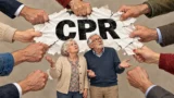 Et ældre ægtepar ser op på et dokument, der holdes af mange hænder, og hvor der står et CPR-nummer, som angiver deres personlige identifikationsnummer.