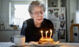 Kirsten, 112 år, puster tre lys ud på en lille fødselsdagskage og markerer dermed et øjeblik i Danmarks historie.