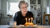 Kirsten, 112 år, puster tre lys ud på en lille fødselsdagskage og markerer dermed et øjeblik i Danmarks historie.